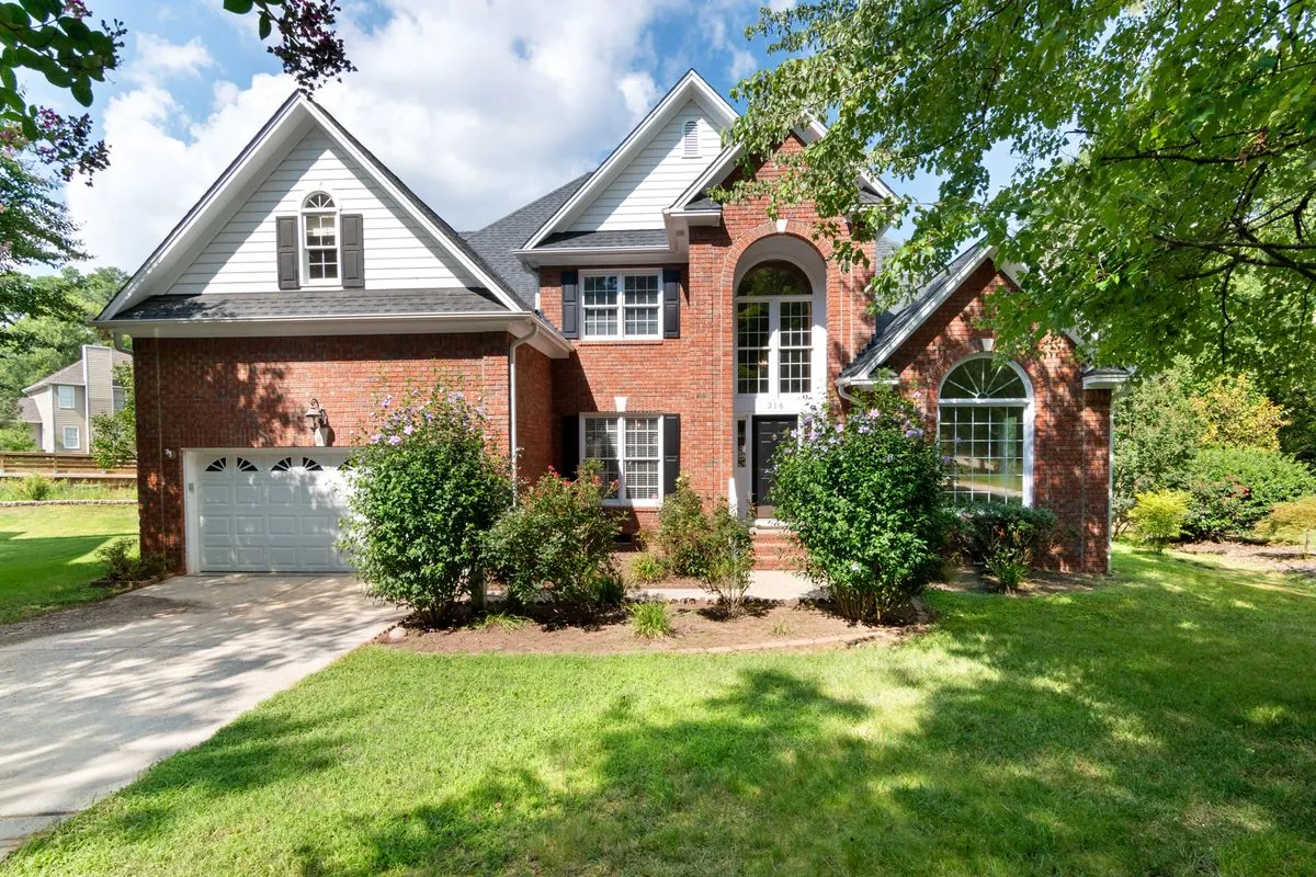 Two-story brick house with a shingle roof and a green front lawn