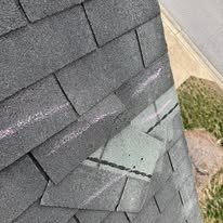 Creased and displaced asphalt shingle near a roof edge