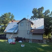 Roofers working on a two-story home with ladders in place
