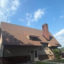 Brown architectural shingle roof on a two-story home with a brick chimney