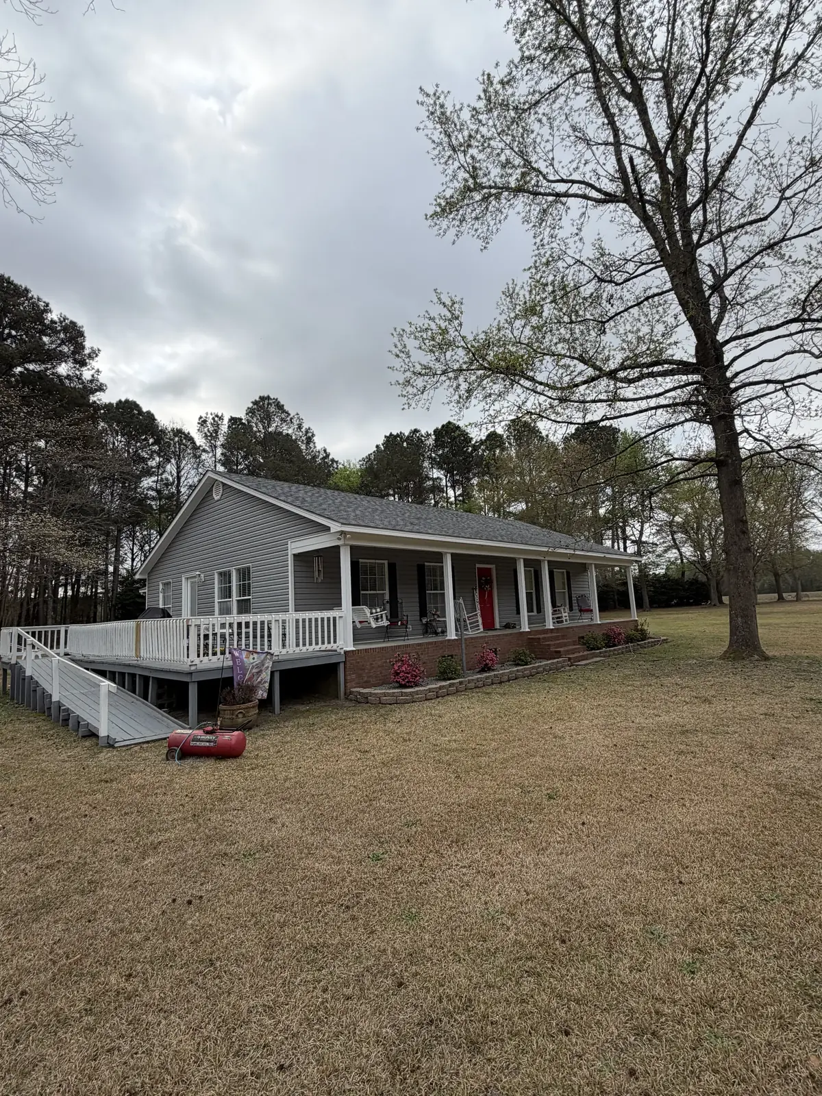 Side porch and deck of a one-story home with a gray shingle roof