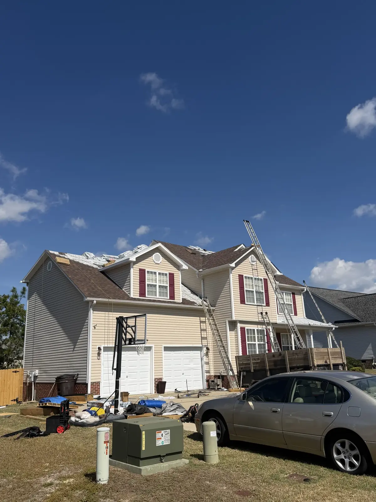 Two-story tan home with work equipment in the yard