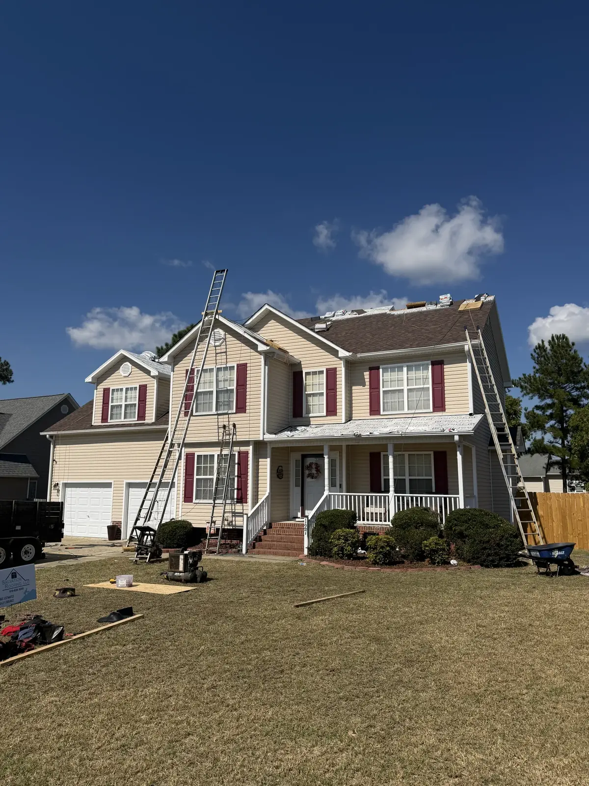 Two-story tan home with ladders against the roof