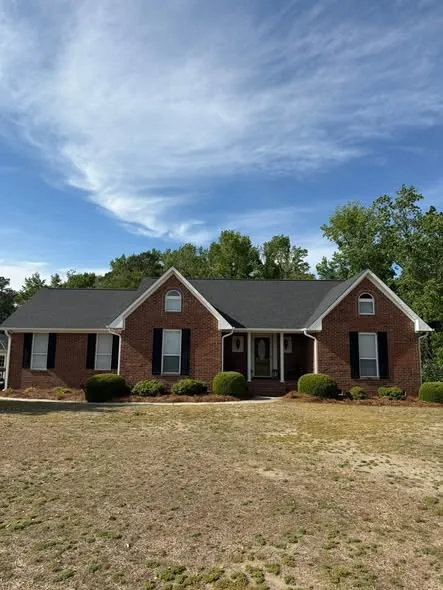 Brick home with dormers and a dark shingle roof