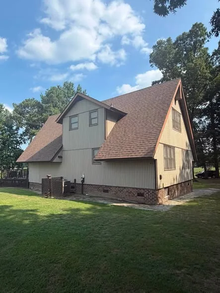Two-story home with a brown shingle roof and brick foundation